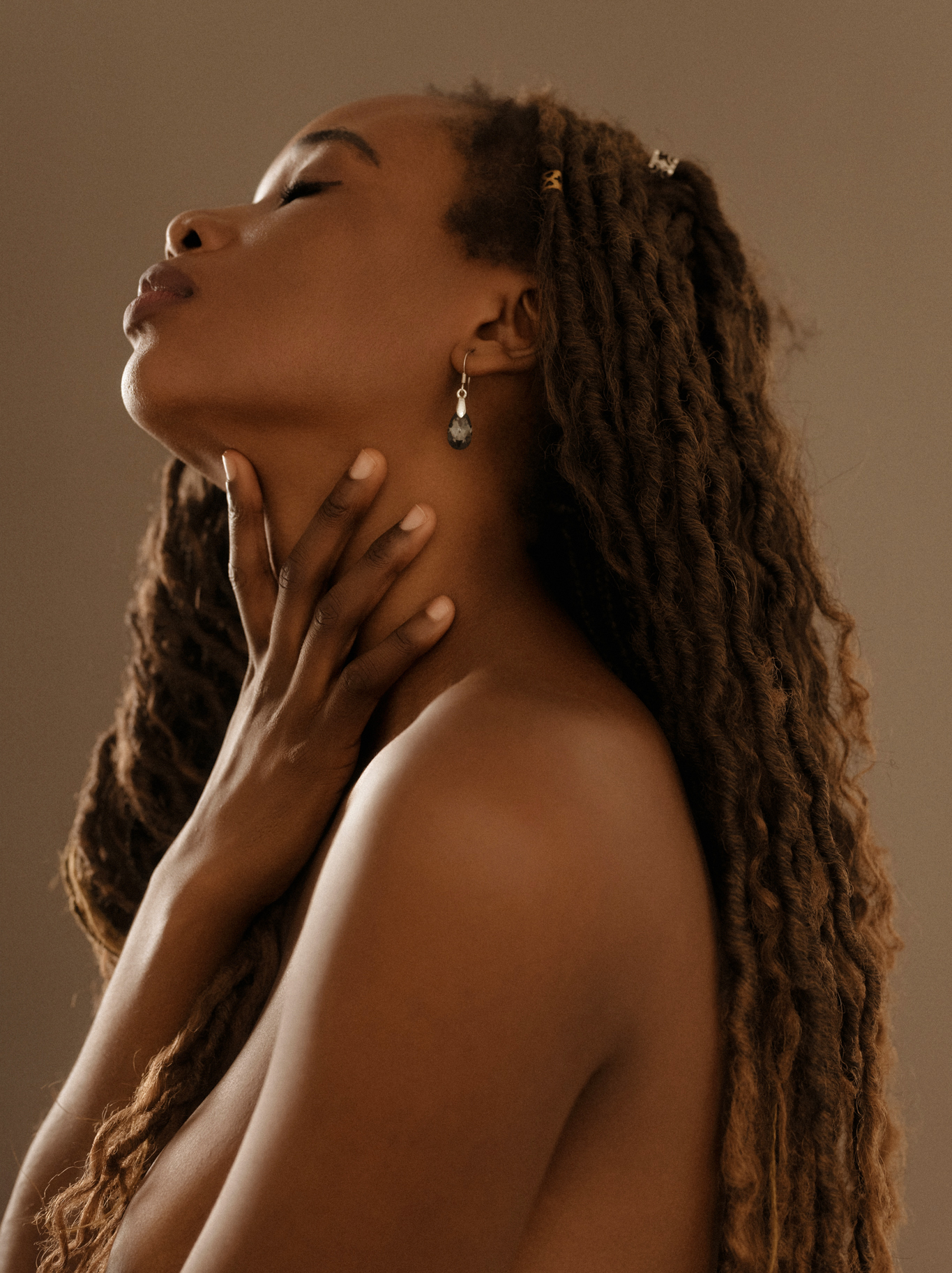 Intimate boudoir photography highlighting natural beauty and confidence; close-up of a woman with dreadlocks, embracing self-love